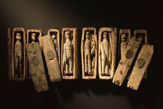 Set of miniature wooden coffins with wooden dolls inside.