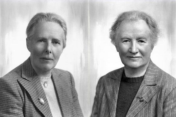 Two women with short hair wearing blazers and jumpers looking to camera placed side by side