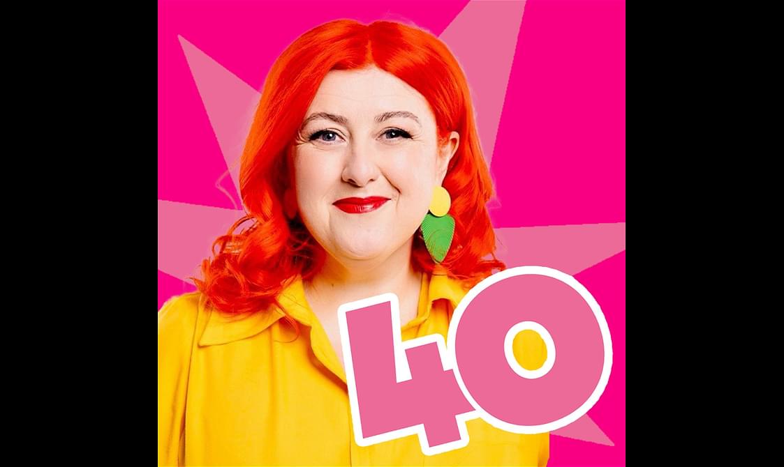 Michelle McManus with red hair and wearing a red dress stands in front of a pink star graphic. The number 40 is in the foreground.