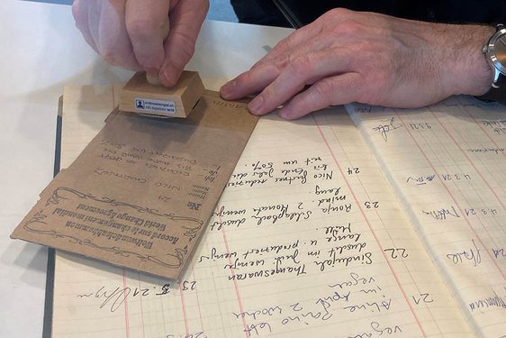 A hand is stamping a pledge, written on a brown piece of paper.