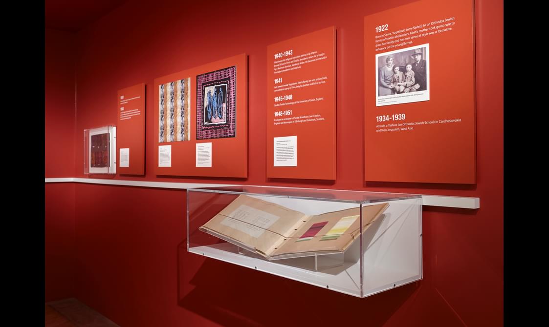 An exhibition room with information boards and a book in a glass display box.