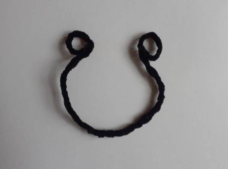 A black pipe cleaner bent into a curve with loops at each end.