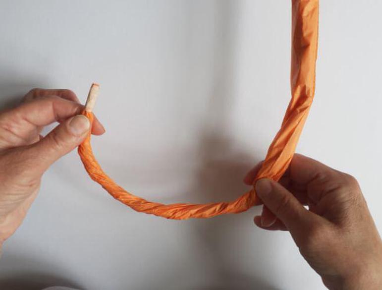 Two hands holding orange paper twisted into a curved shape.