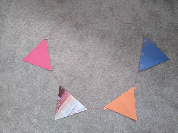 Four buntings in various colours tied to a red string, arranged in a circular pattern.